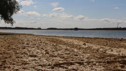 Anglian Water A long, dry bank of a reservoir with the bed of water in the distance.
