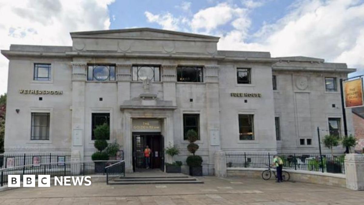 A queue of people line up outside the Golden Beam pub.