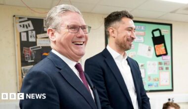 Sir Keir Starmer and Damian Egan stand together in a classroom where children are sitting at desks. Both me are wearing suits and the children are in school uniform.