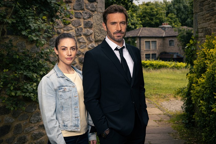 Isabel Hodgins as Victoria and Oliver Farnworth as John Sugden in Emmerdale, Hodgins in a denim jacket and Farnworth in a suit