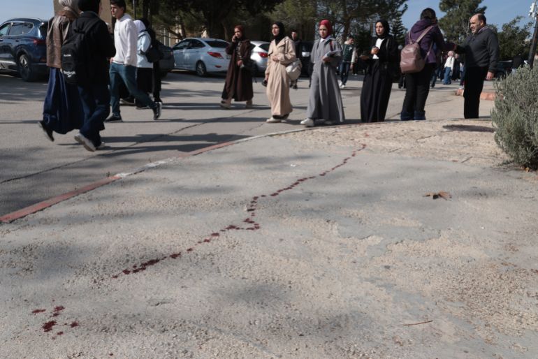 epa12630732 People walk past bloodstains on the ground where Palestinian students were injured during an Israeli military raid on the Birzeit University campus near Ramallah, West Bank, 06 January 2026. According to the Palestinian Health Ministry and Palestinian Red Crescent Society, at least 11 students were wounded after Israeli forces stormed the campus on 06 January. EPA/ALAA BADARNEH