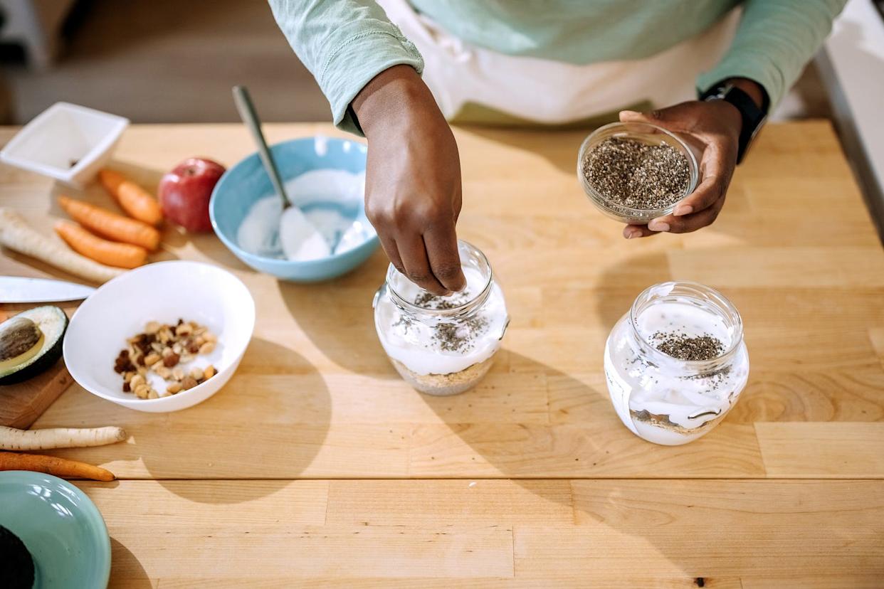 person sprinkling chia seeds on yogurt