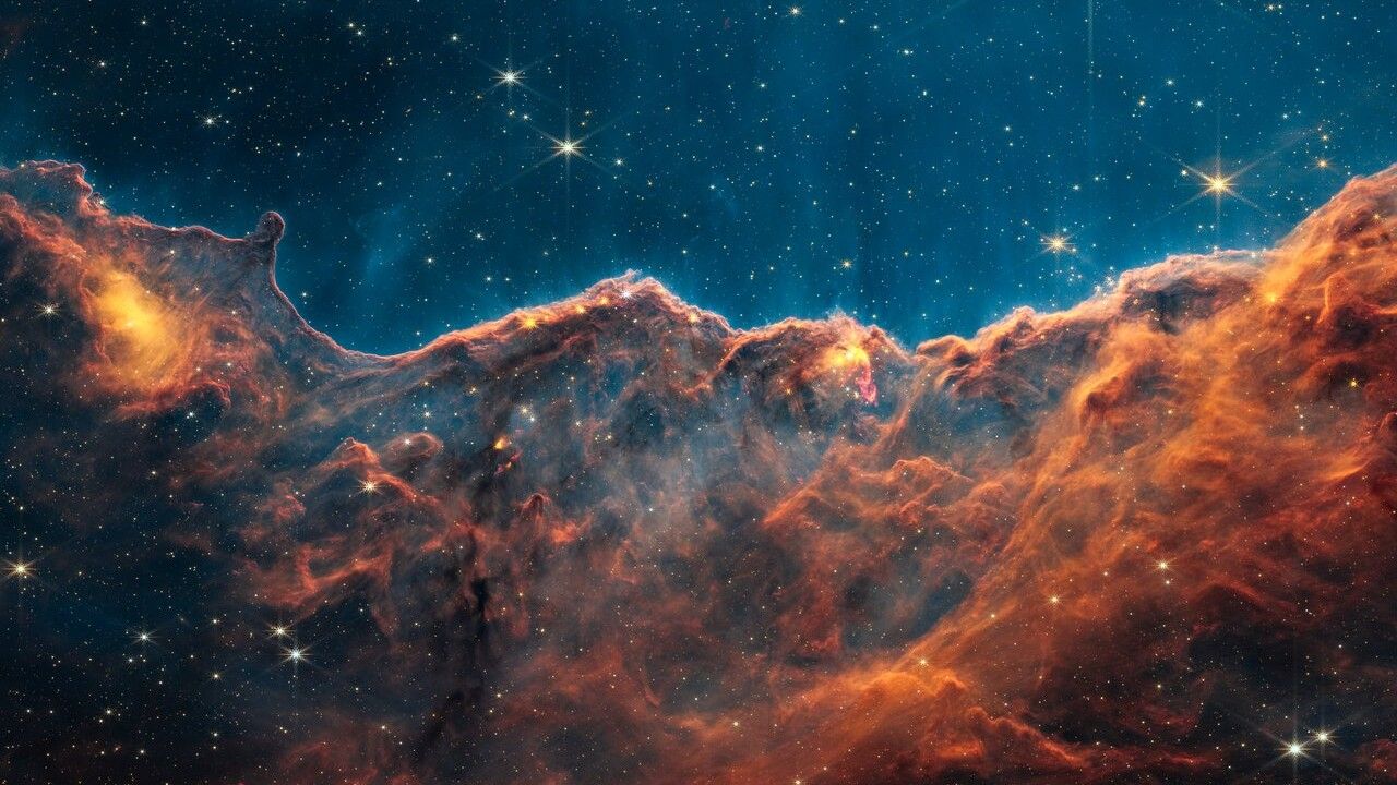orange clouds of dust in space look like mountains in the JWST image