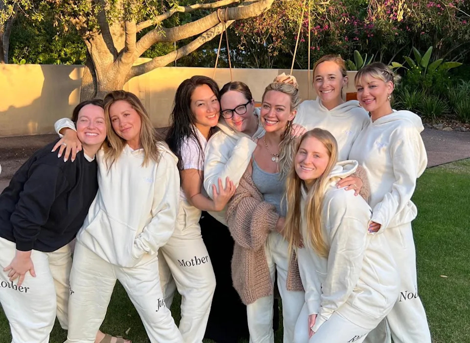 Group of women outdoors, all smiling and wearing matching comfortable outfits with "Mother" printed. Casual and relaxed setting