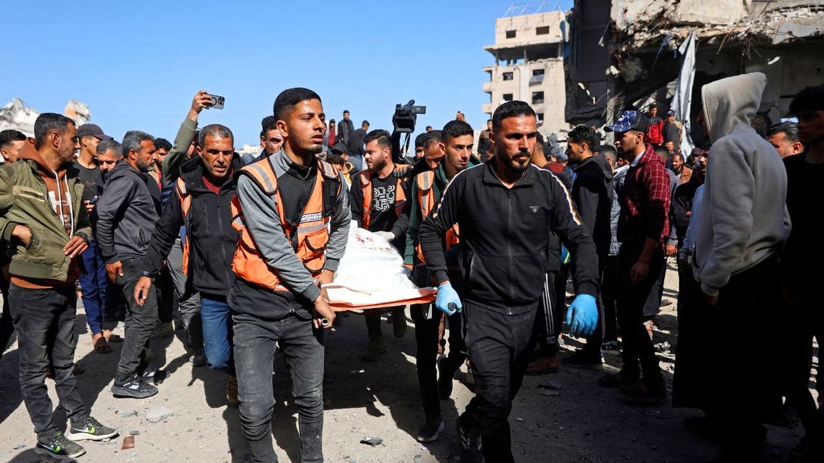 Rescuers carry a body through debris after an Israeli airstrike on a police station in Gaza City.