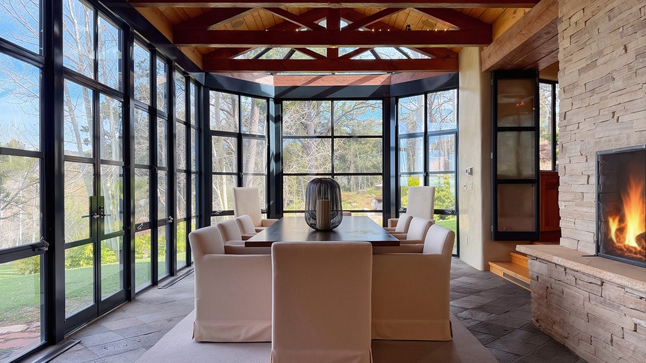The dining room features a table in a room with glass all around.