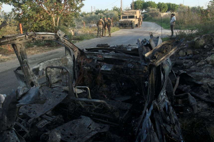 Members of the Lebanese army stand in front of a car targeted by an Israeli airstrike on Hezbollah operatives outside the town of Jouaiya, Lebanon, on January 7.