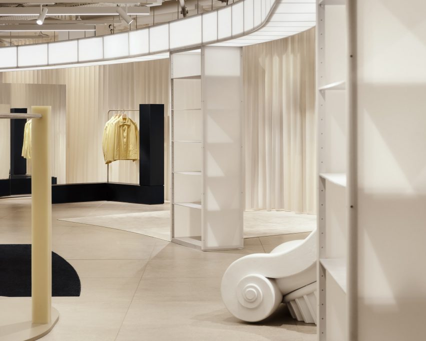 White shopping space with floor sculpture and yellow rail