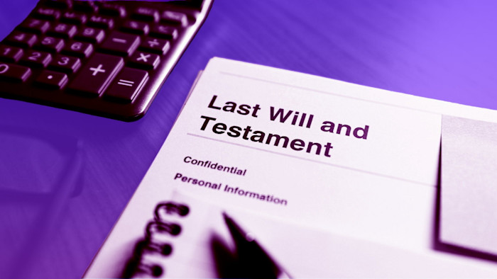 A document labelled "Last Will and Testament" on a desk next to a calculator and notepad.