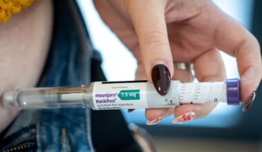 A hand holds a Mounjaro KwikPen injection pen, labeled 7.5 mg tirzepatide, pressed against bare skin.
