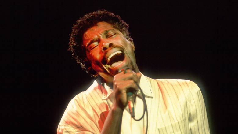 Billy Ocean singing in light shirt with dark background