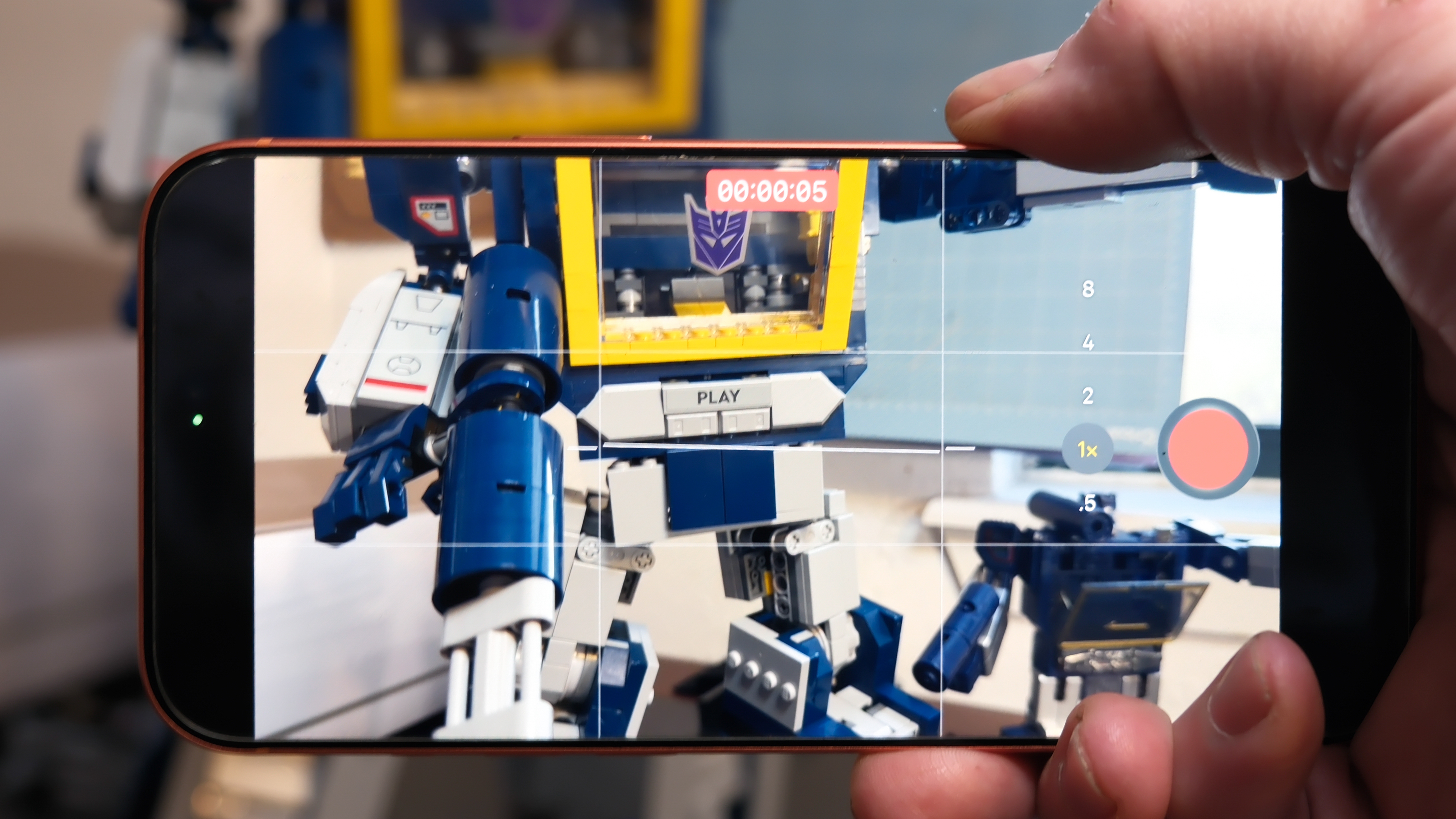 Camera Control button software features on the Apple iPhone 17 Pro Max in Cosmic Orange color, showing zoom, switching cameras, Magnifier app, and more
