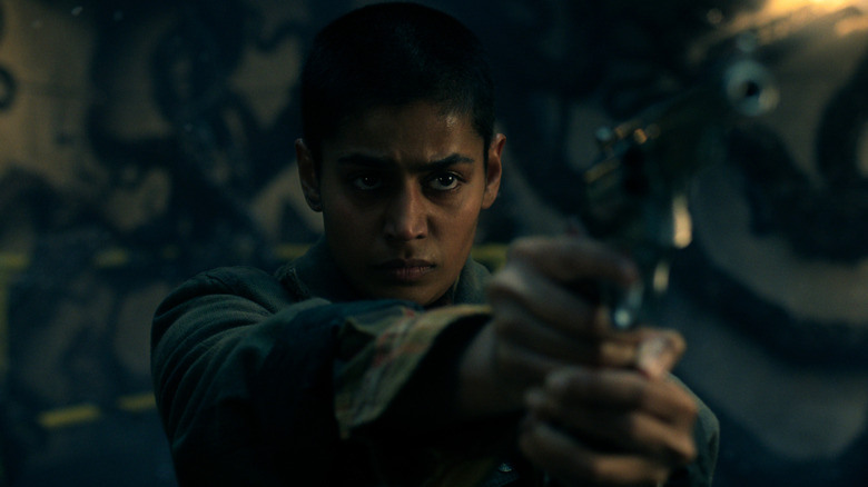 Kali points a gun in 