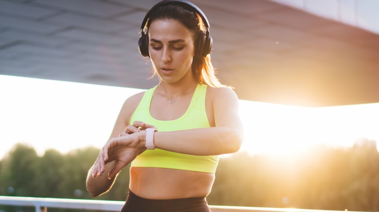 Woman listening to music through her smartwatch and headphones while jogging