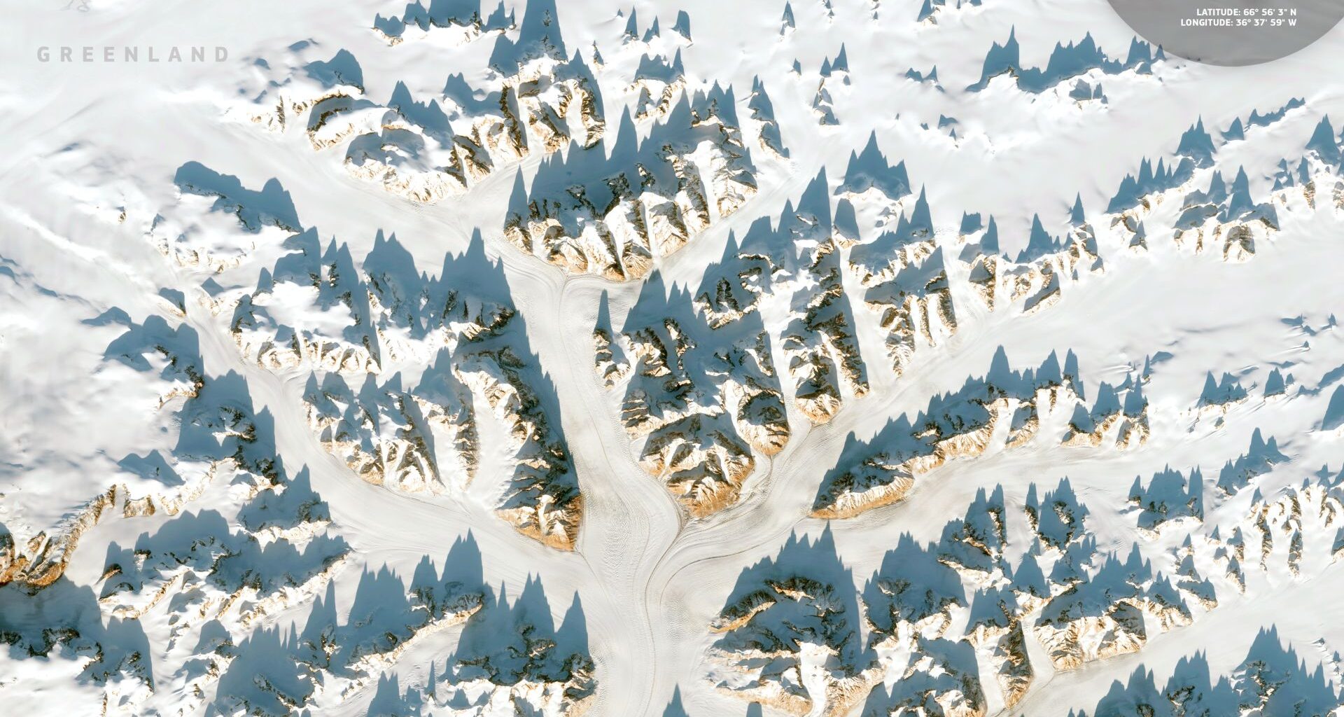 A series of snow-covered mountain peaks jut out against a white landscape in an image seen from space