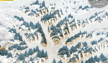 A series of snow-covered mountain peaks jut out against a white landscape in an image seen from space