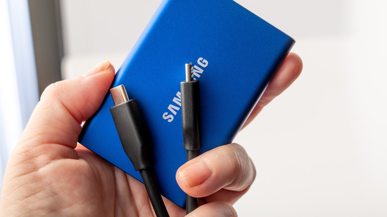 Holding a Samsung external SSD and USB-C cable