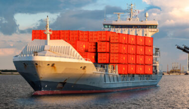 Container ship leaving a dock carrying containers illustrated with the flag of China. Credit: Adobe