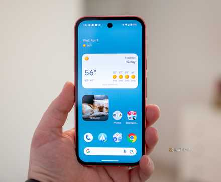 Person holding the Google Pixel 9a showing the home screen.