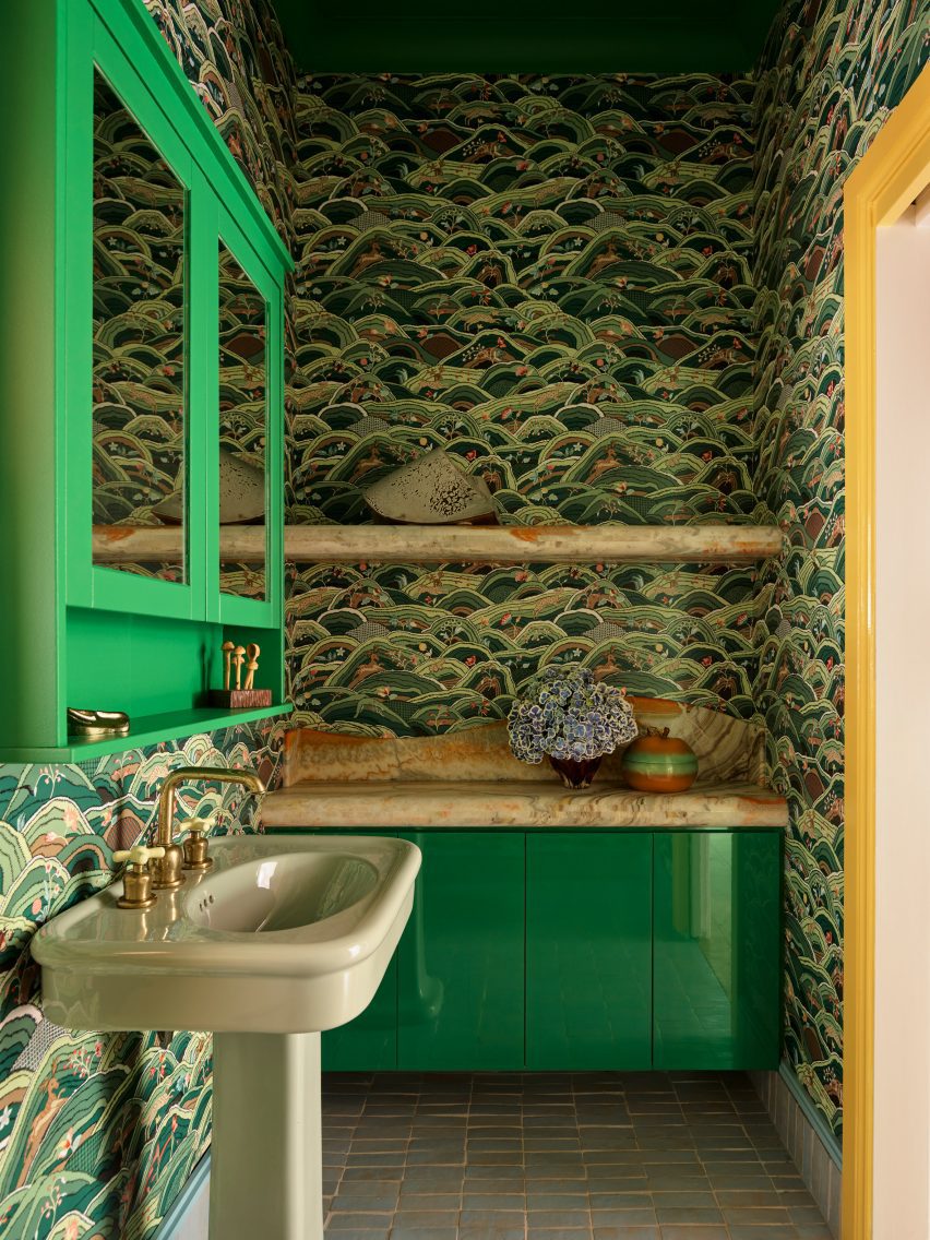 Bathroom with green cabinets and wallpaper