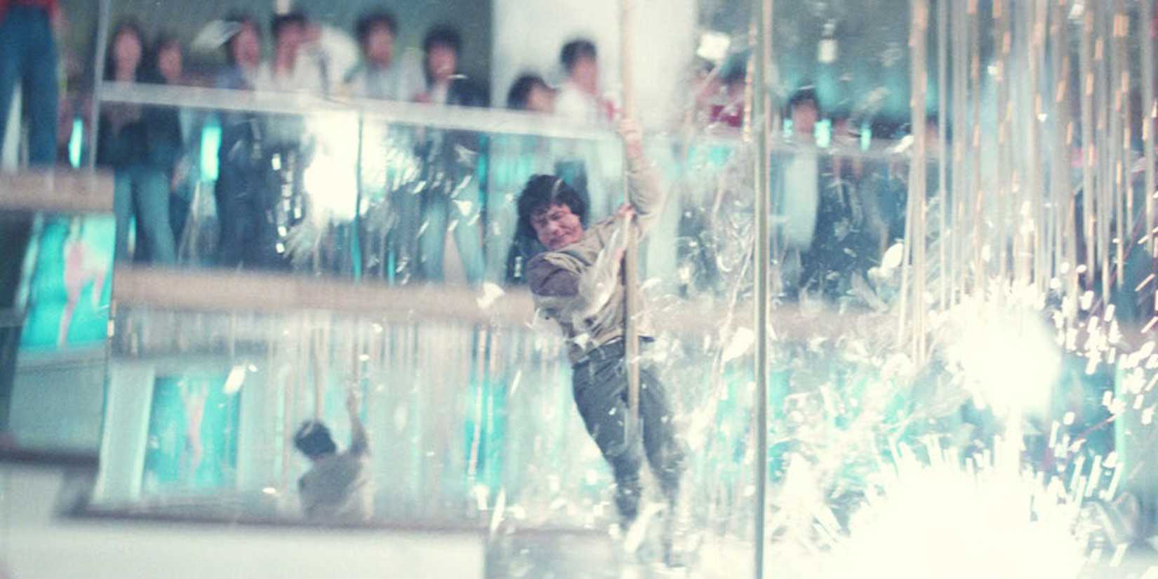 Jackie Chan swinging from a pole above an explosion of sparks in Police Story.