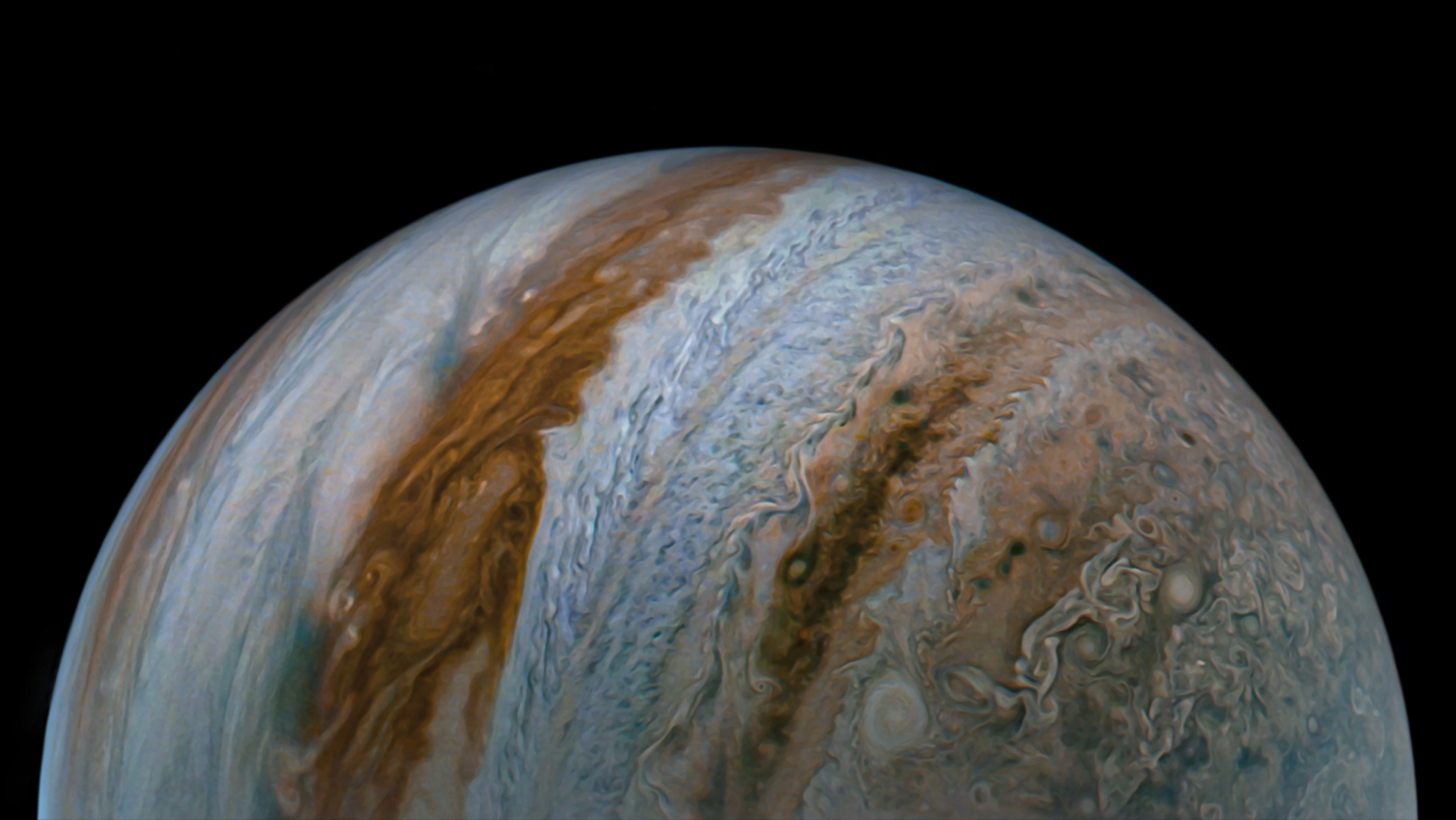 A close up of the planet Jupiter in space, its various orange and brown atmospheric layers curving almost vertically.