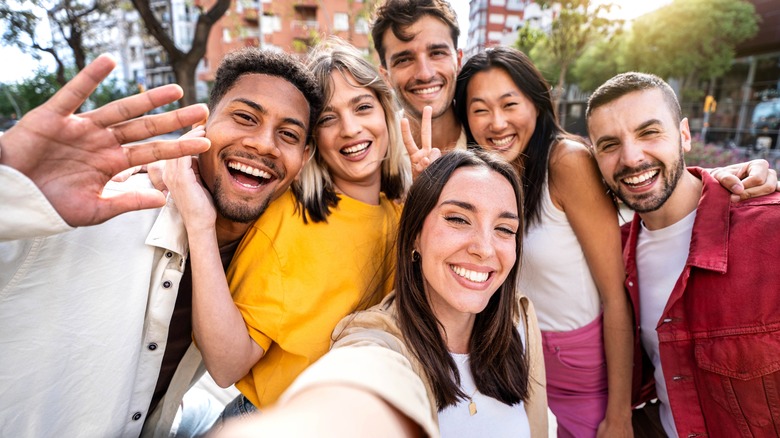 Several cheerful people taking a group selfie with a smartphone