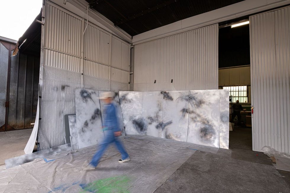 art studio with person walking and spraypainted canvases