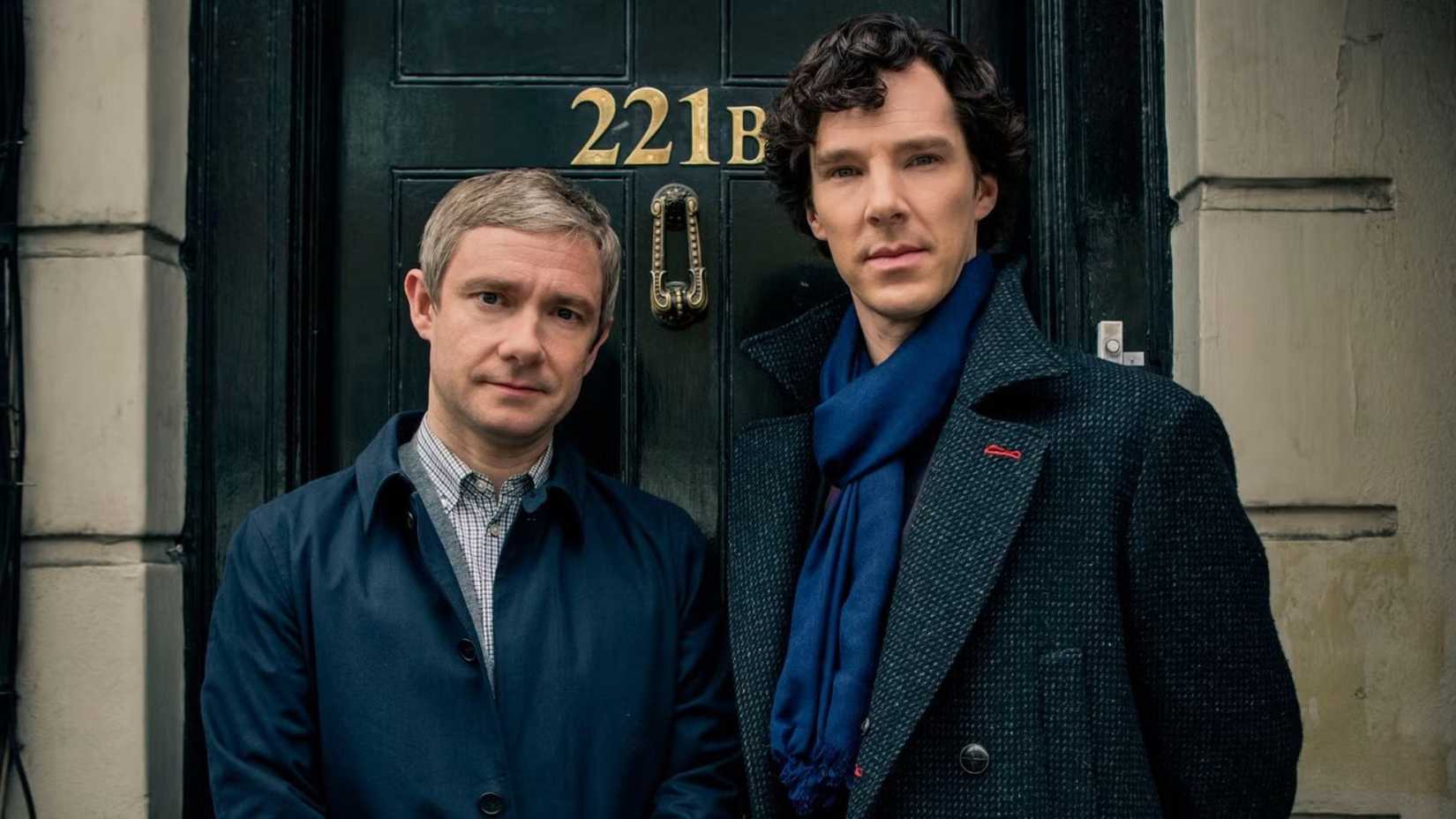 Two men stand in front of a door the says 221B in Sherlock.