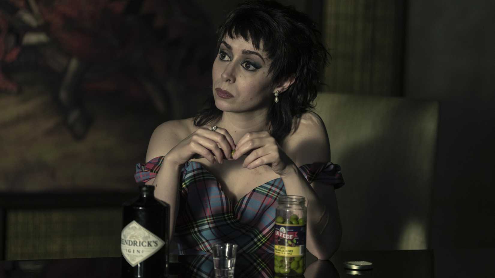 Cristin Milioti Sofia Falcone sitting at a table touching her hands together in The Penguin