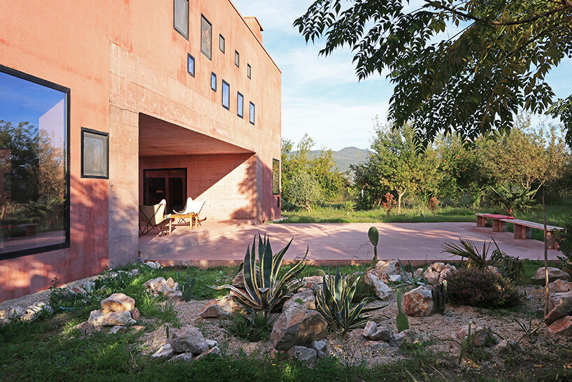 square openings punctuate the facade of courtyard-centric red house in albania