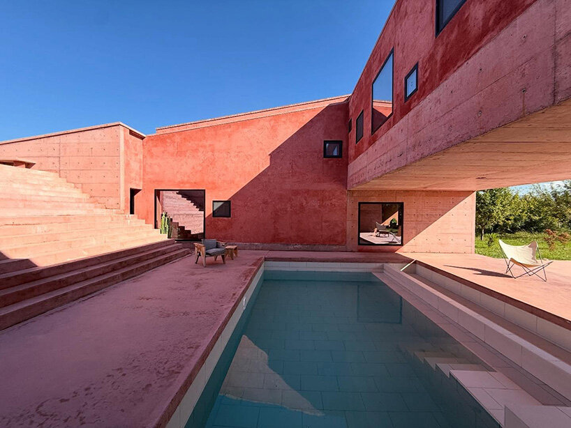 square openings punctuate the facade of courtyard-centric red house in albania