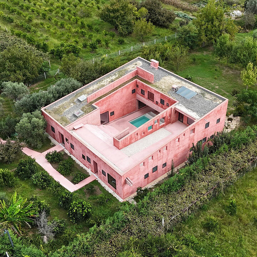 square openings punctuate the facade of courtyard-centric red house in albania