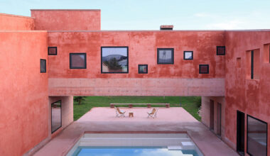 square openings punctuate the facade of red house in albania