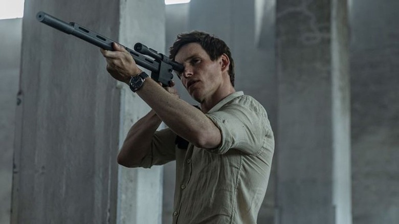 The Jackal (Eddie Redmayne) aims a rifle while standing in The Day of the Jackal