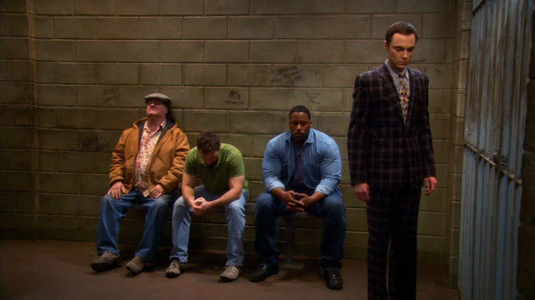 Sheldon standing in a jail cell with other people on The Big Bang Theory