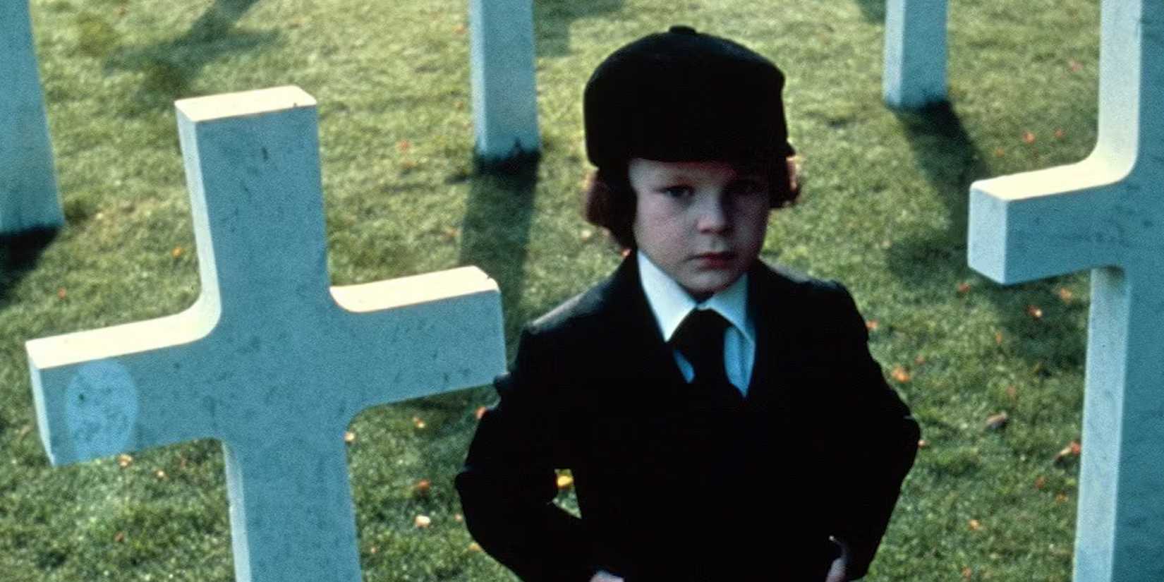 Damien stands in a graveyard in The Omen.