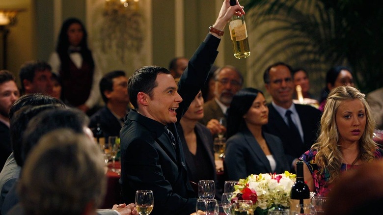 Sheldon raising a bottle of wine at an event on The Big Bang Theory