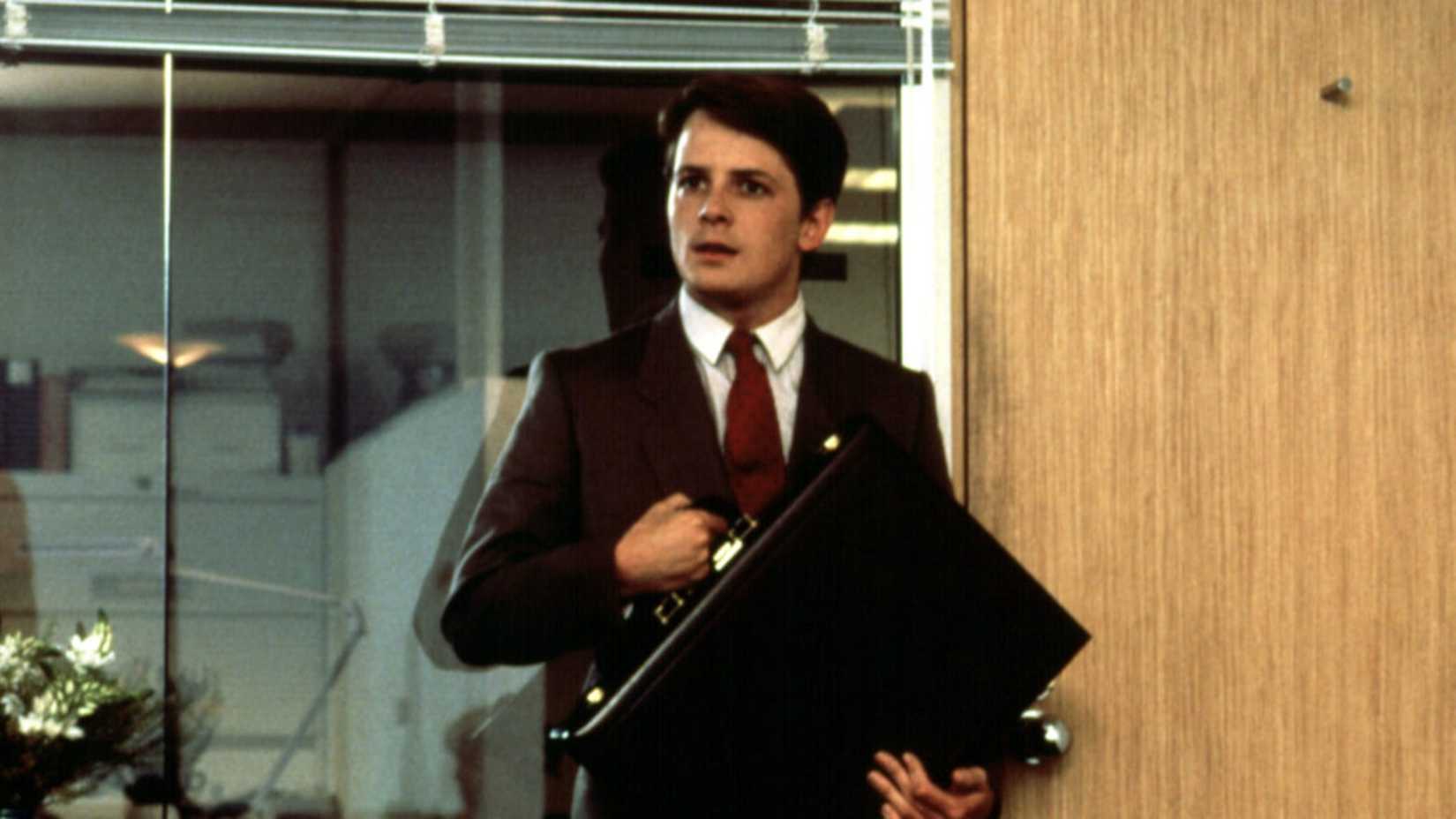 Michael J. Fox stands with a briefcase in The Secret of My Success