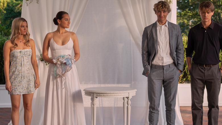 Taylor, Belly, Jeremiah, and Conrad stand in front of a white curtain in 