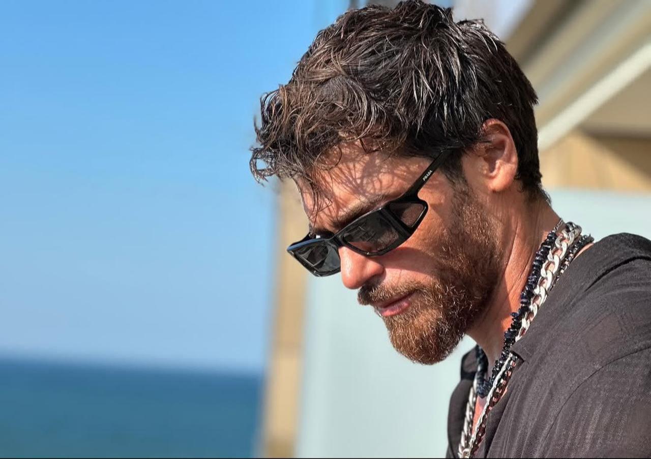 Can Yaman photographed on a balcony overlooking the sea, sharing a relaxed summer moment, June 26, 2025. (Photo via Instagram/@canyaman)
