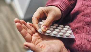A person's hands popping white pills out of a blister pack.