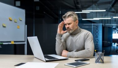 A person looks upset while looking at a laptop.