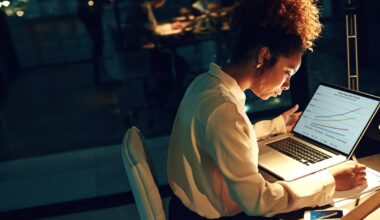 An investor looks at something on a laptop in a darkened office.
