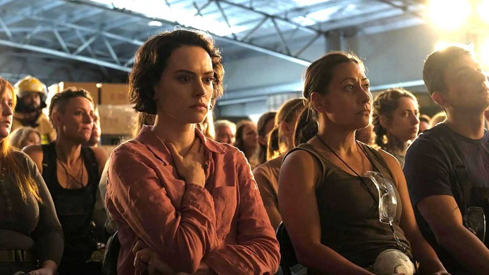 In a scene from We Bury the Dead, Daisy Ridley stands in a crowd of volunteering receiving orientation for the job of cleaning up a litany of dead bodies following a horrific accident.