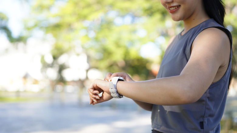 a woman outside looking at her smartwatch