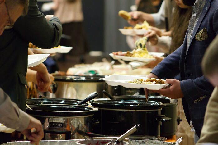 People serving food from slow cookers at a buffet, illustrating stories of patients leaving the hospital against medical advice