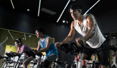 Young people riding stationary bike during indoor cycling class in gym.