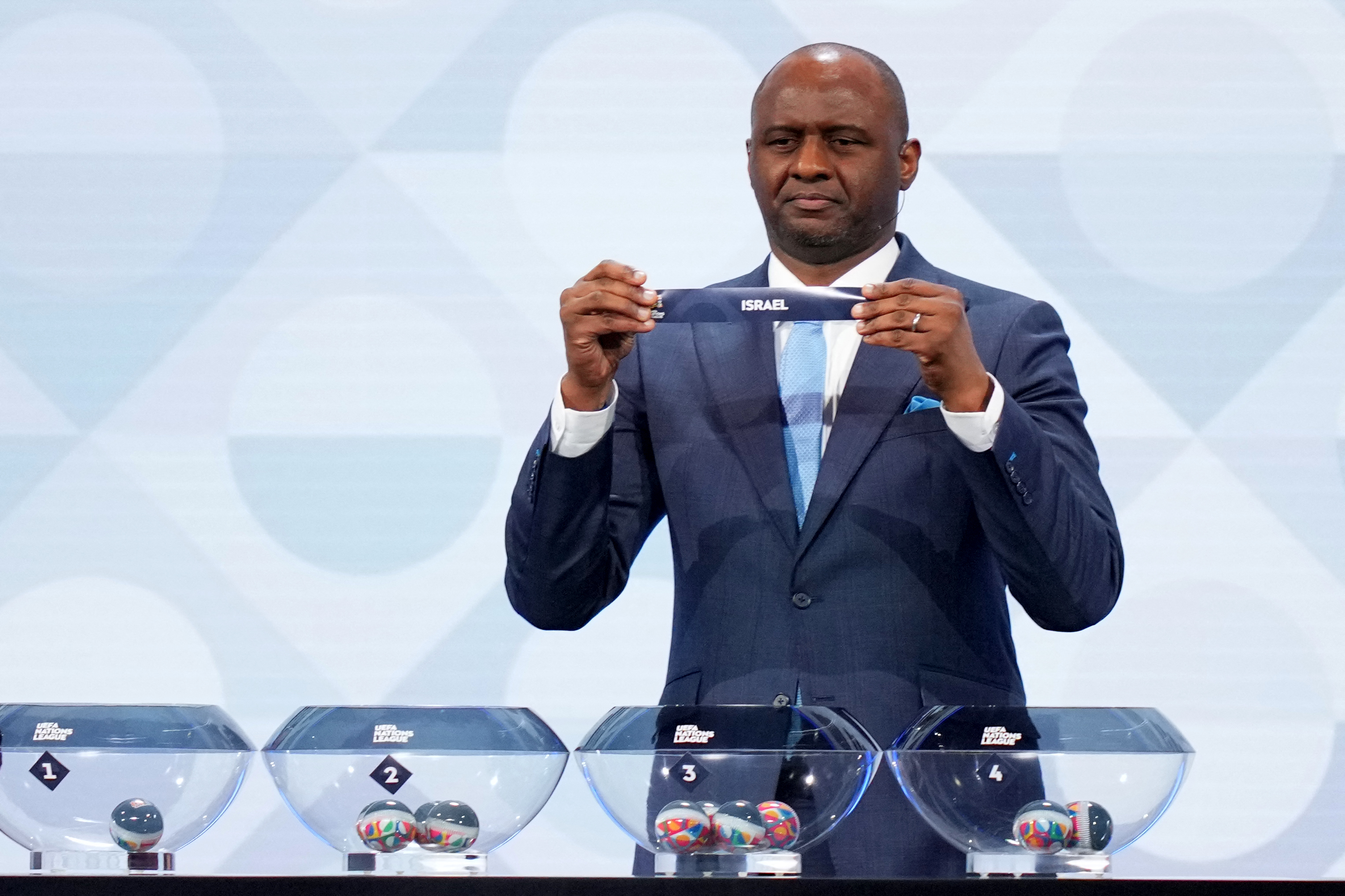 Former French international Patrick Vieira holds up a paper slip that reads "Israel" during the UEFA Nations League draw ceremony.