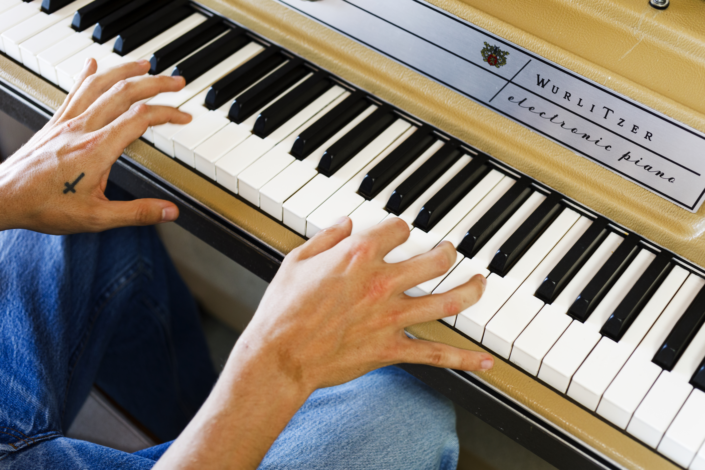 A person's hands playing a Wurlitzer electronic piano.
